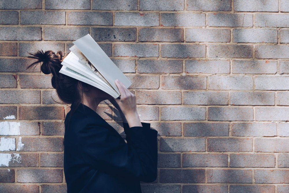 woman covering her face with white book photo